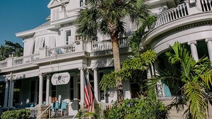 A large white building with a balcony, palm trees, and a brick pathway leading to the entrance. - Amsterdam's Curry Mansion Inn (Key West)