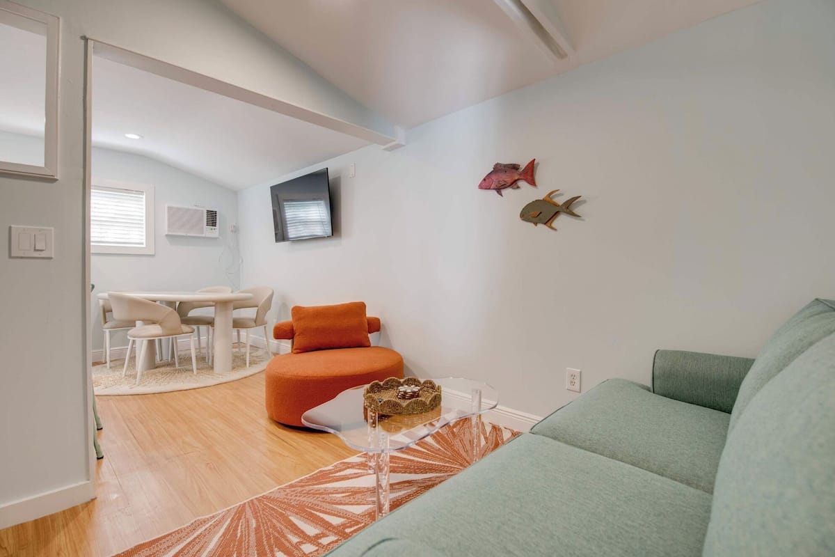 Ein modernes Wohnzimmer mit einer Couch, einem Esstisch mit Stühlen und Wanddekoration.