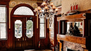 A grand room with a large wooden door, a fireplace with a mantelpiece, and a chandelier. - Amsterdam's Curry Mansion Inn (Key West)