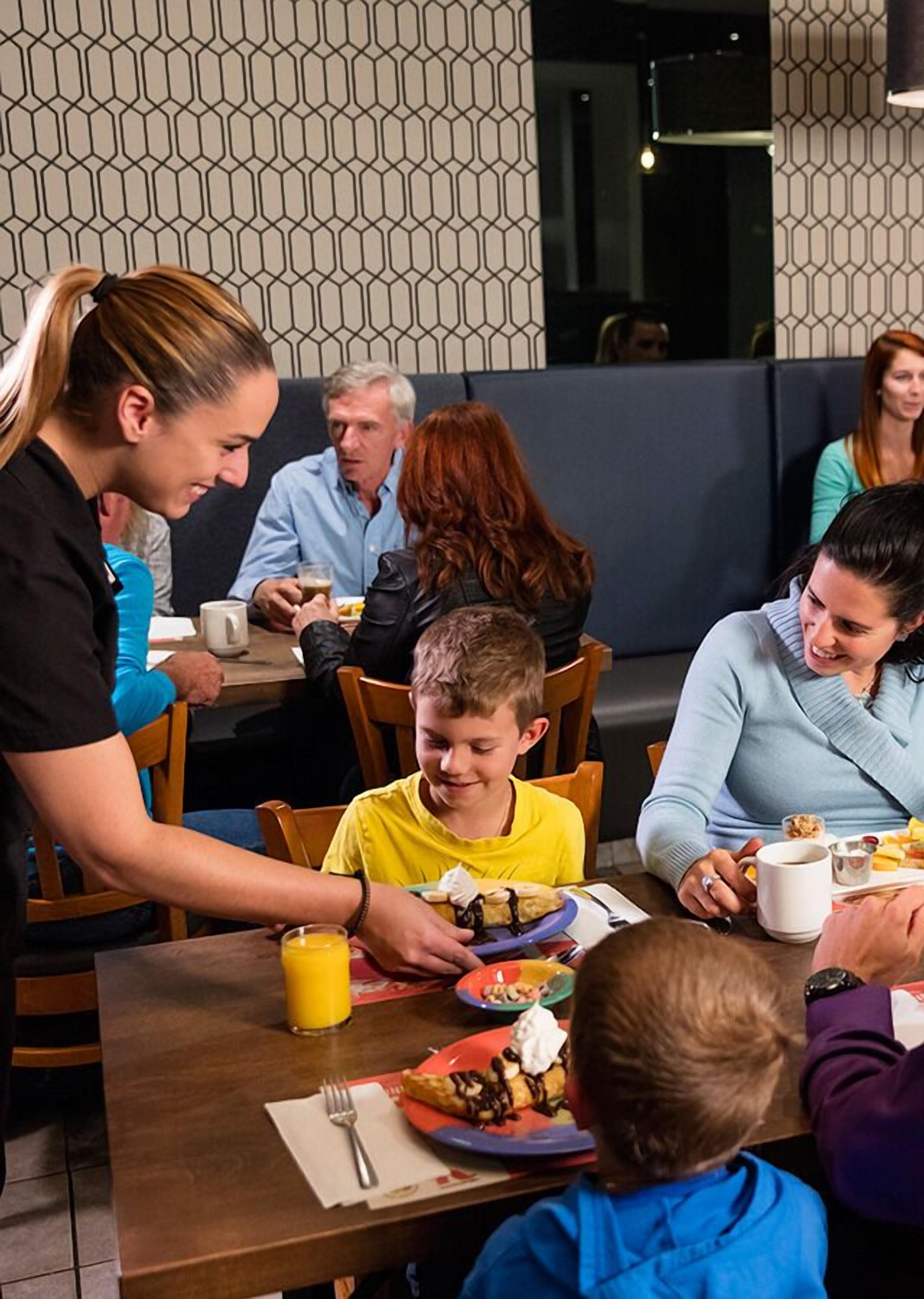 Un grupo de personas cenando en un restaurante con una pared decorada con un diseño geométrico al fondo.