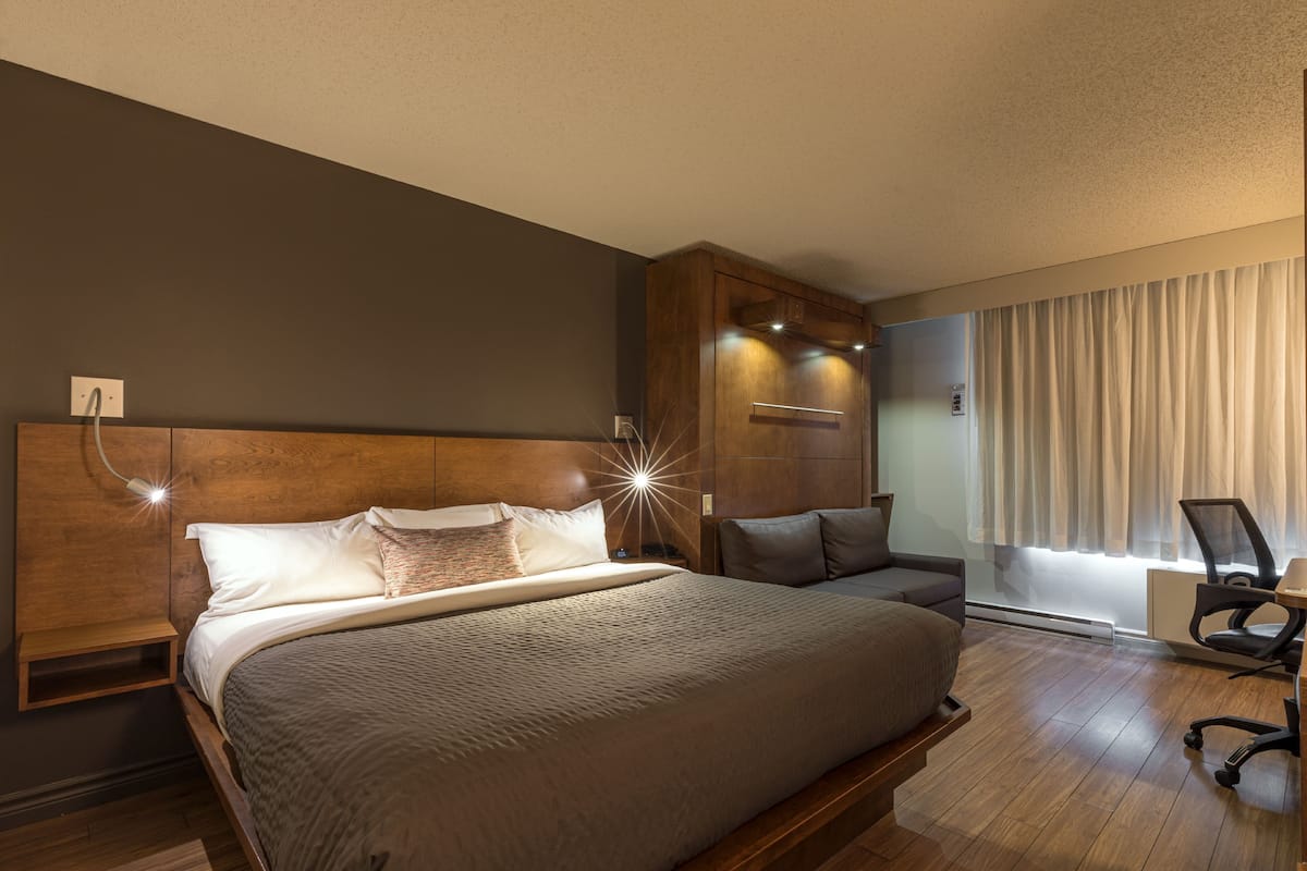 A modern hotel room with a large bed, a desk, and a chair.