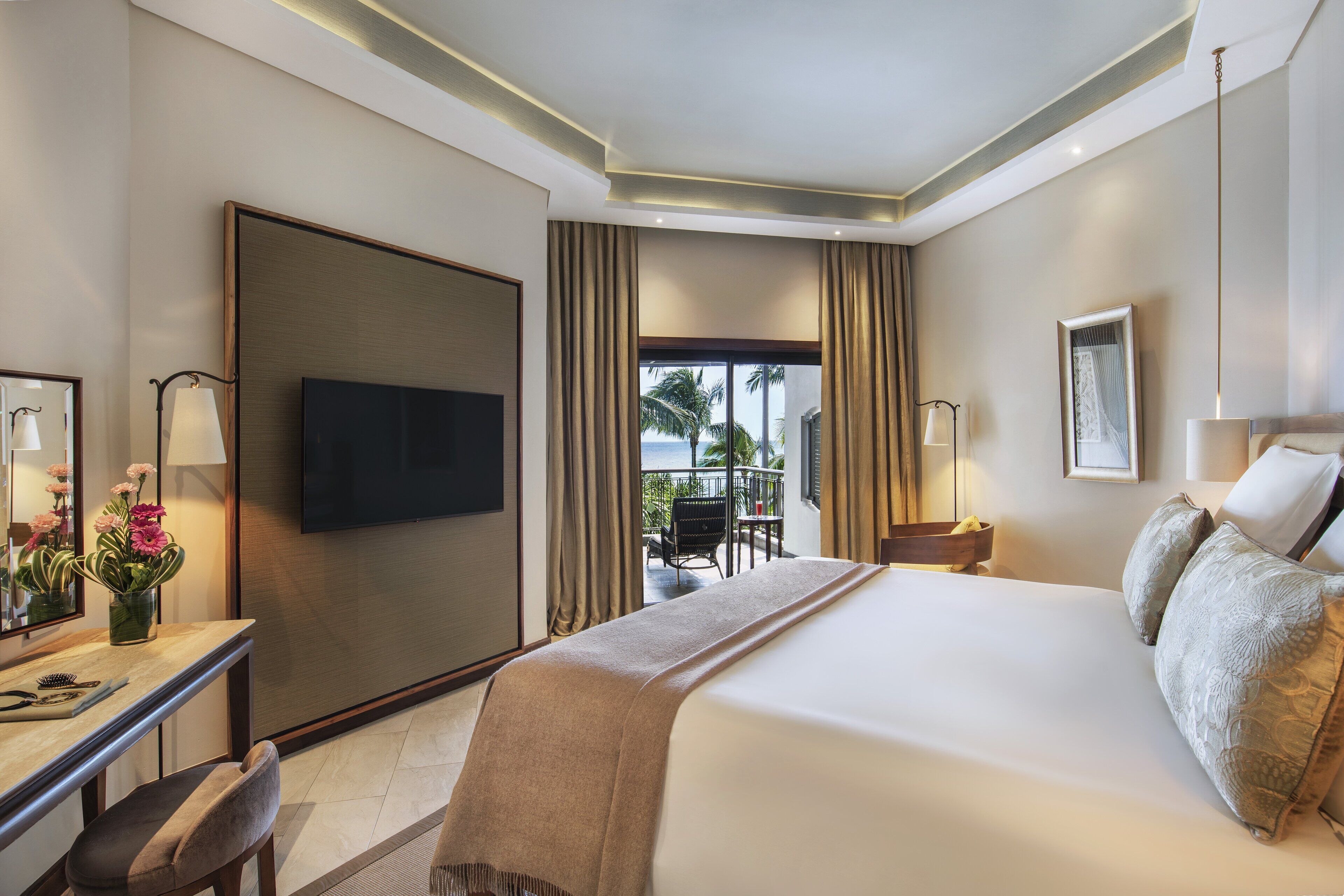 A hotel room with a large bed, a desk with a chair, a television, and a view of the outdoors.