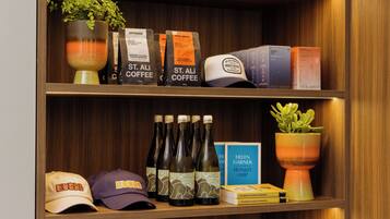 Una estantería con bolsas de café, un libro y una planta en maceta.