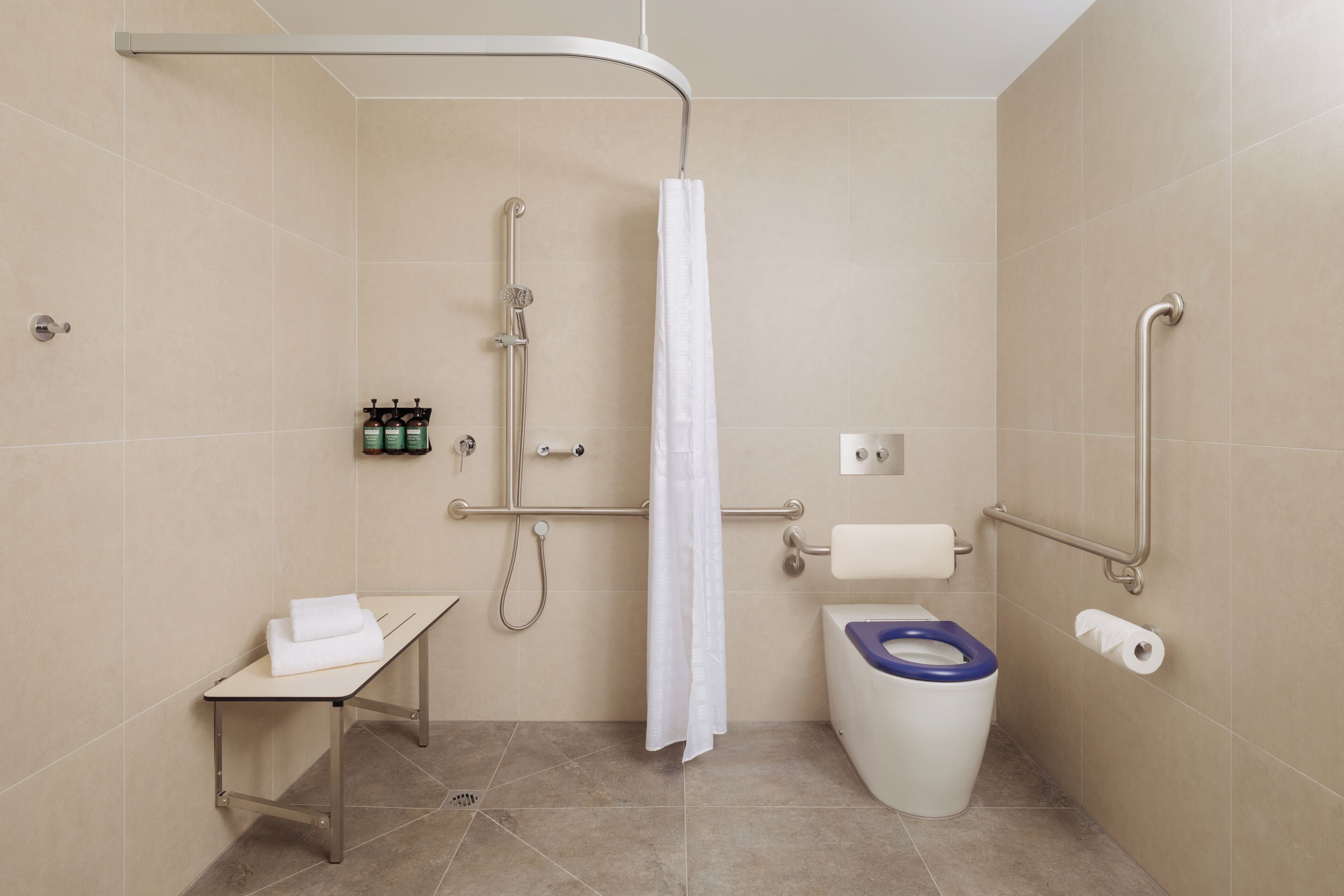 Un baño moderno con ducha, inodoro y una pequeña mesa con una toalla.