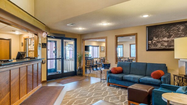 A hotel lobby with a reception desk, a blue sofa, and a dining area in the background. - Quality Inn Pueblo North (Pueblo)