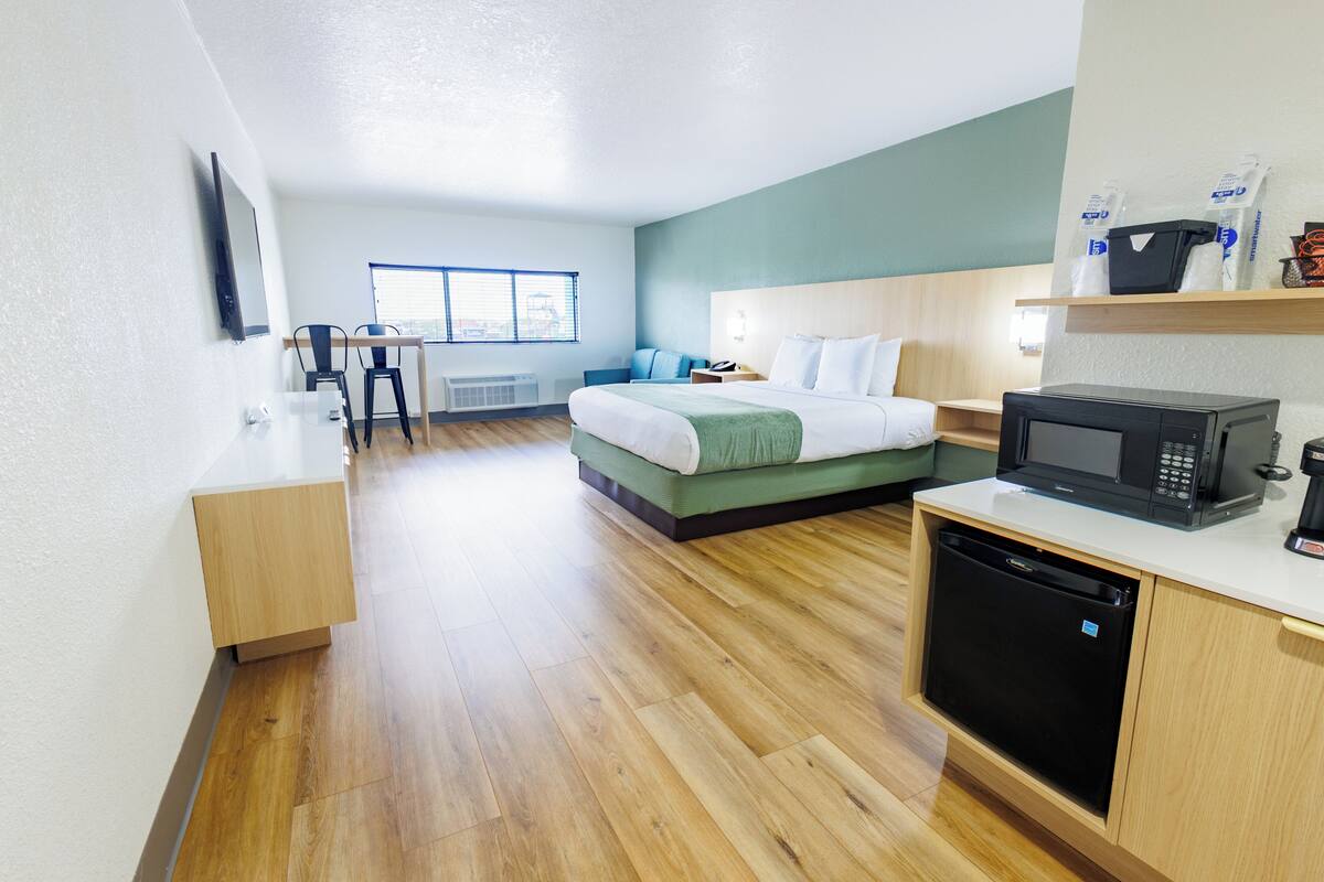 Quarto de hotel moderno com uma cama, uma escrivaninha, micro-ondas e lava-louças.
