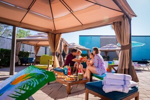 A covered outdoor seating area with tables, chairs, and umbrellas.