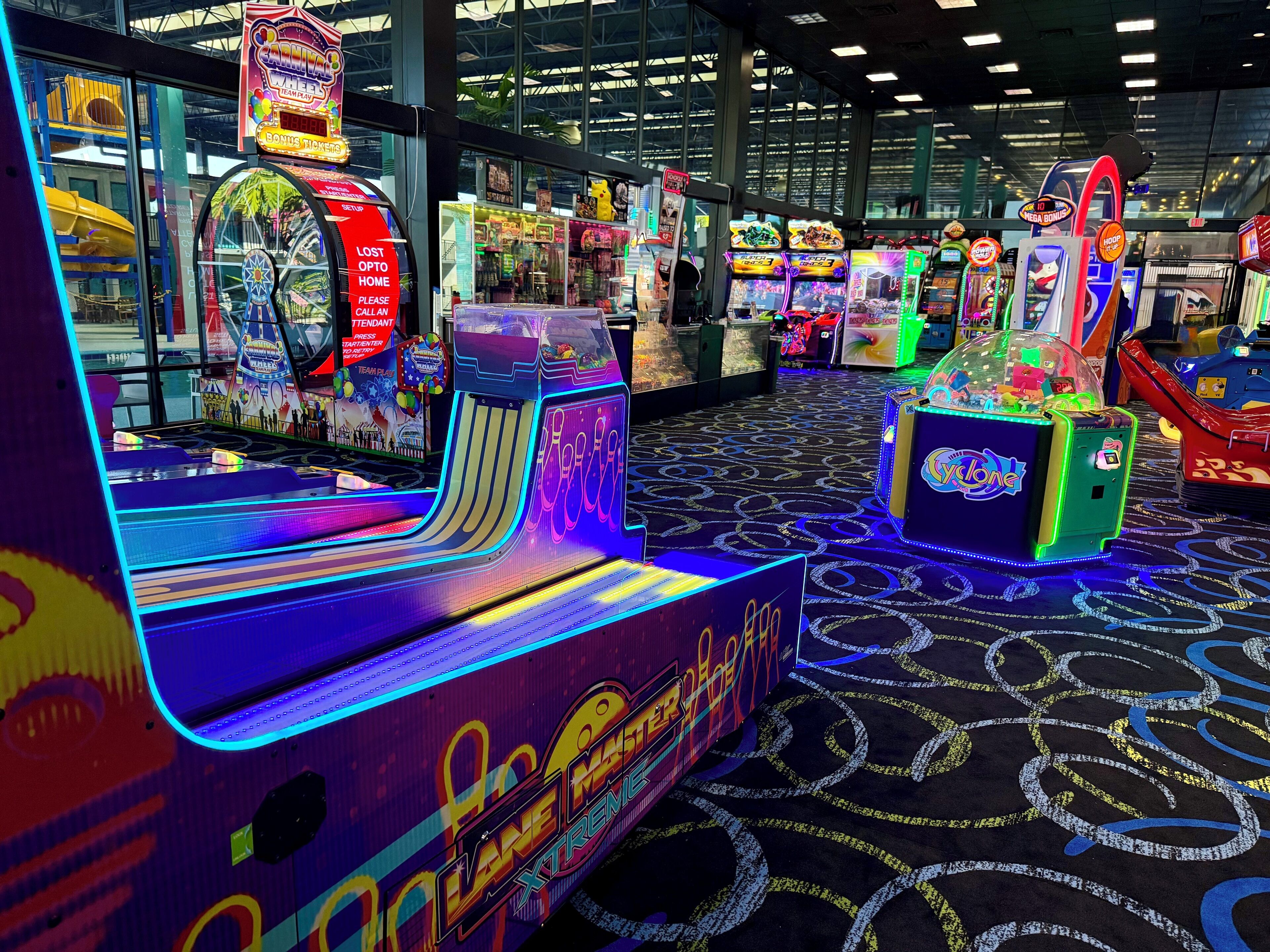 A brightly lit arcade with various gaming machines, including a 'Lane Max' game and a 'Mega Bonus' game.