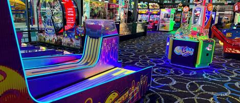 Un salón de juegos muy iluminado con diversas máquinas, incluyendo el juego 'Lane Max' y el juego 'Mega Bonus'.