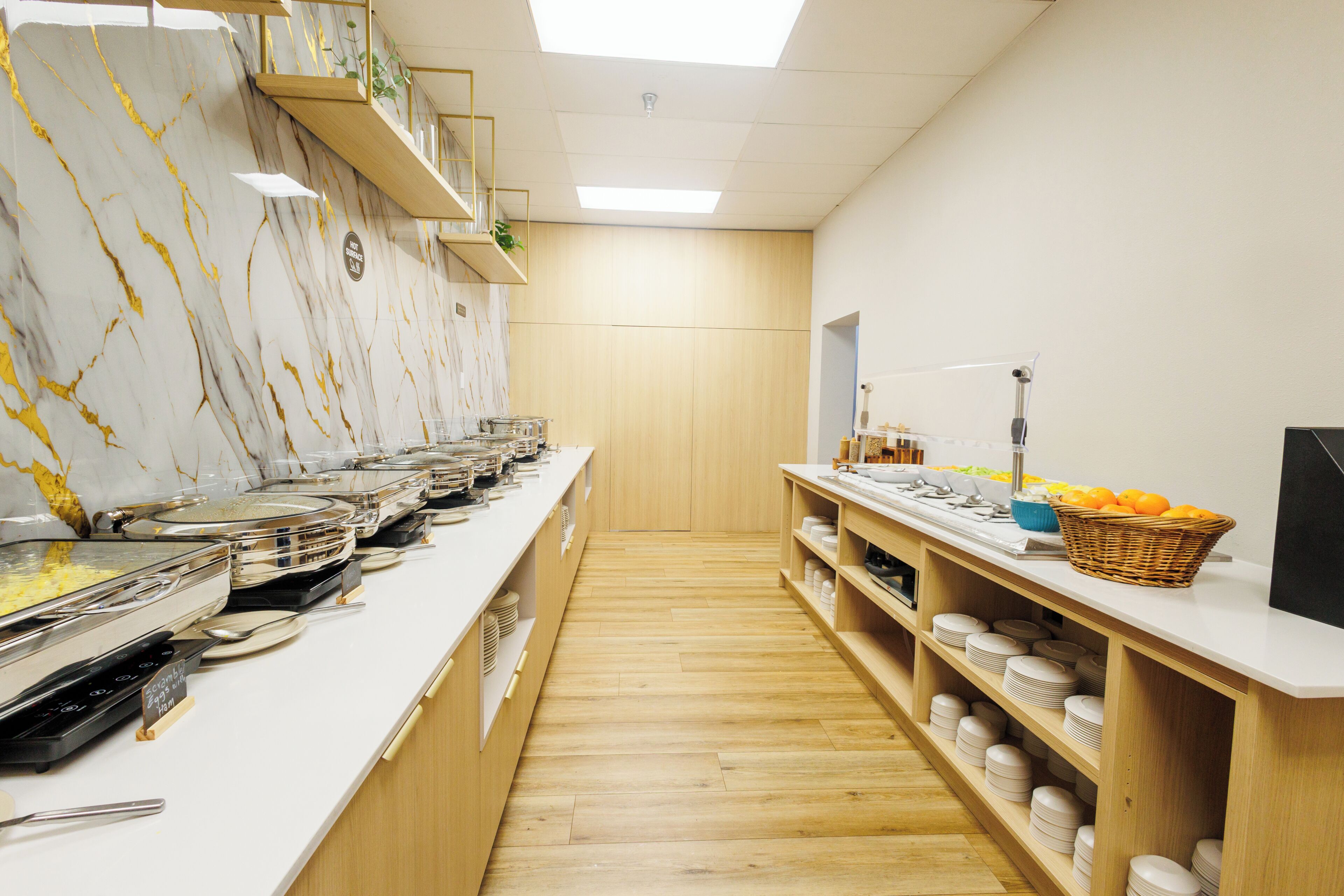 A buffet setup with various food stations, wooden shelving, and a marble wall.