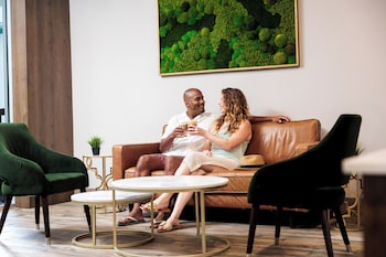Two people seated in wicker chairs, reading magazines, with a black wall and a hanging light fixture in the background. at Coco Key Hotel & Water Park Resort