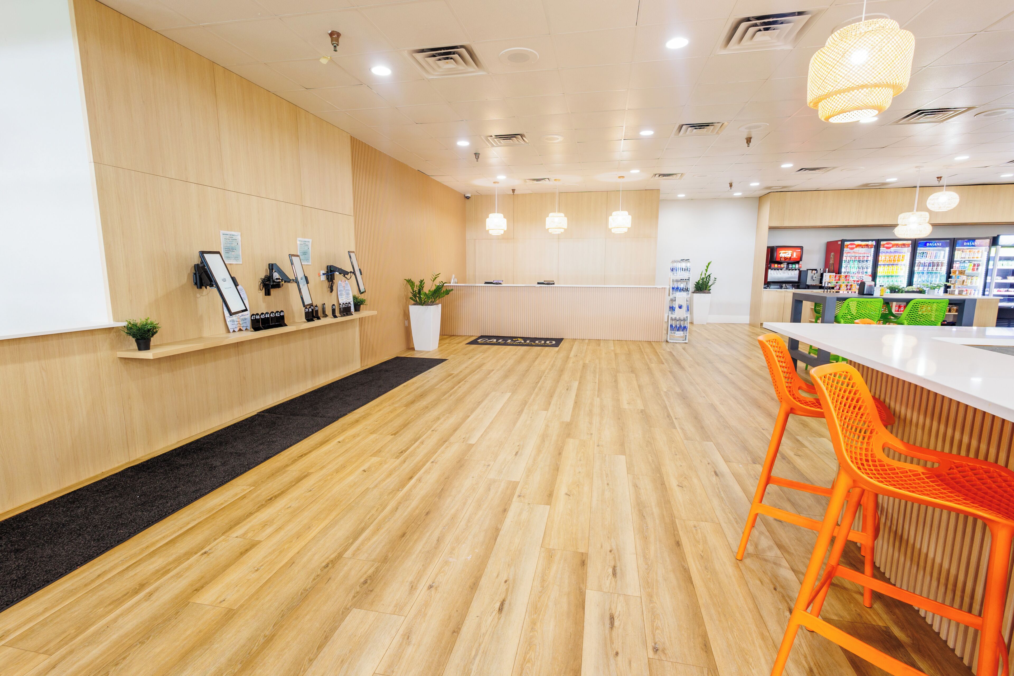 A reception area with a wooden floor, a reception desk, orange chairs, and a counter with a menu.