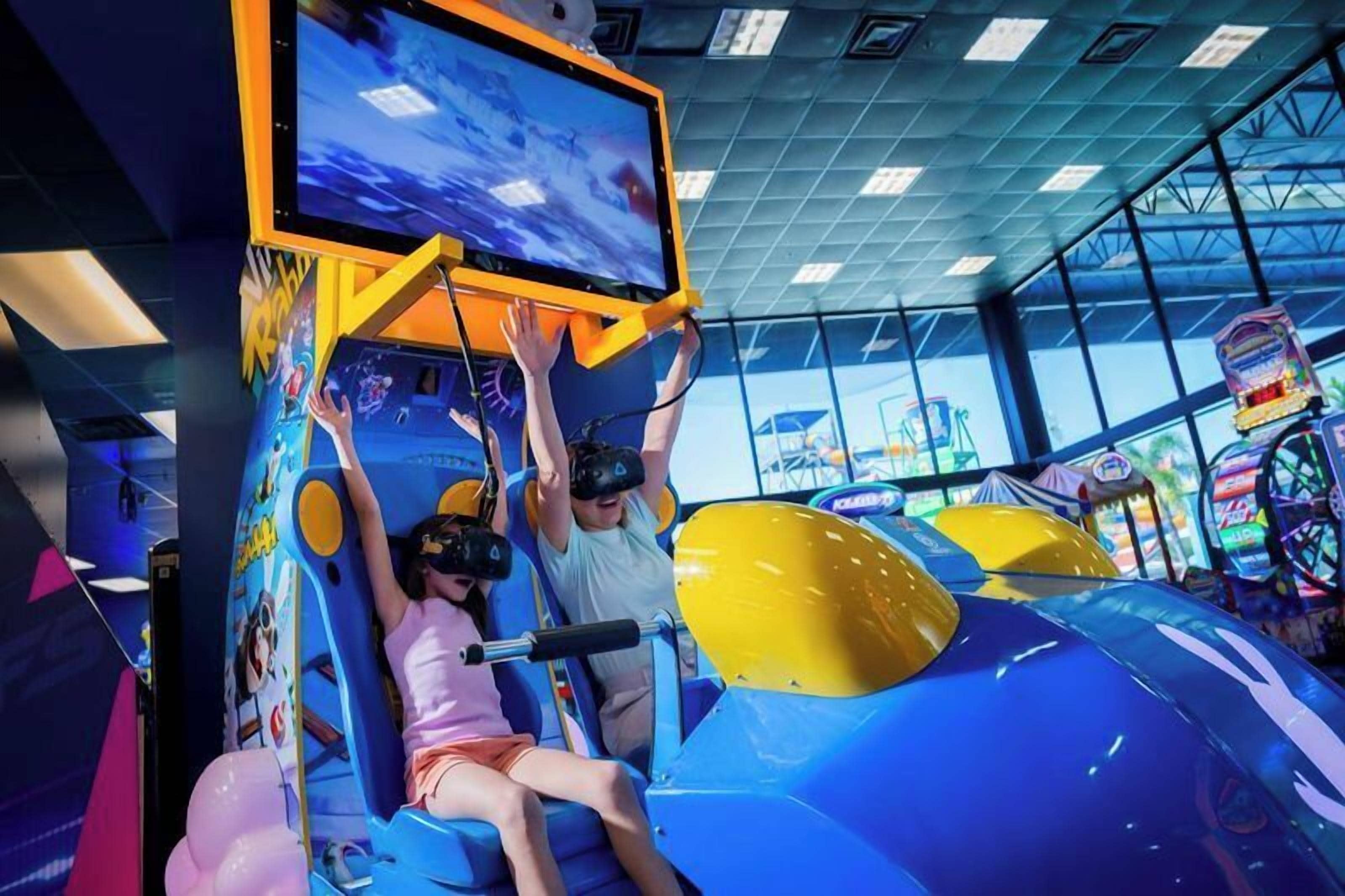 A VR gaming setup with a large screen and two people wearing VR headsets.