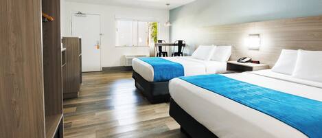 A hotel room with two beds, a desk, and a wardrobe.