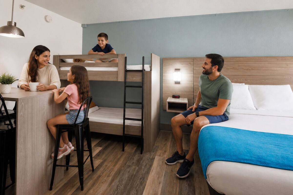 Quarto com beliche, escrivaninha, mesa de cabeceira e cama com cobertura azul.