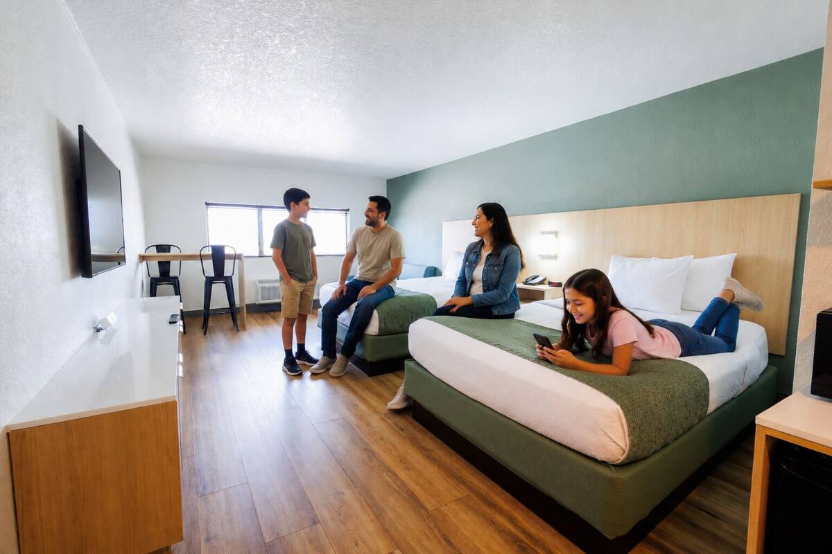 Quarto de hotel com cama, escrivaninha e televisão.
