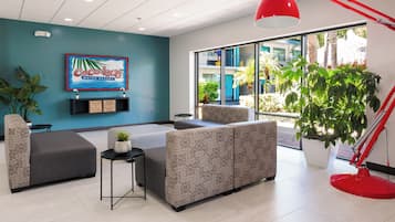 Un hall d’entrée moderne avec une grande fenêtre, un luminaire suspendu rouge et une enseigne indiquant le Coco Key Water Resort.