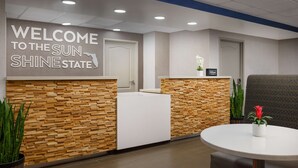 Un área de recepción con una pared de madera, un mostrador de recepción, una mesa redonda y un banco rojo.