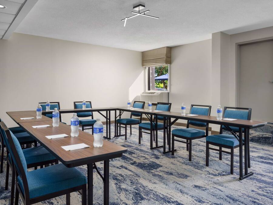 Ein Konferenzraum mit einem langen Tisch, blauen Stühlen und Wasserflaschen.