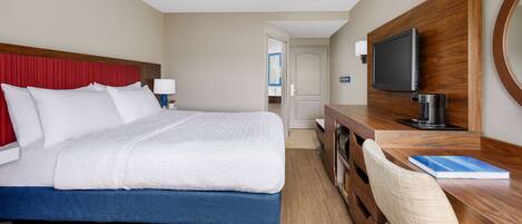 A hotel room with a bed, a desk with a chair, a television, and a coffee maker.
