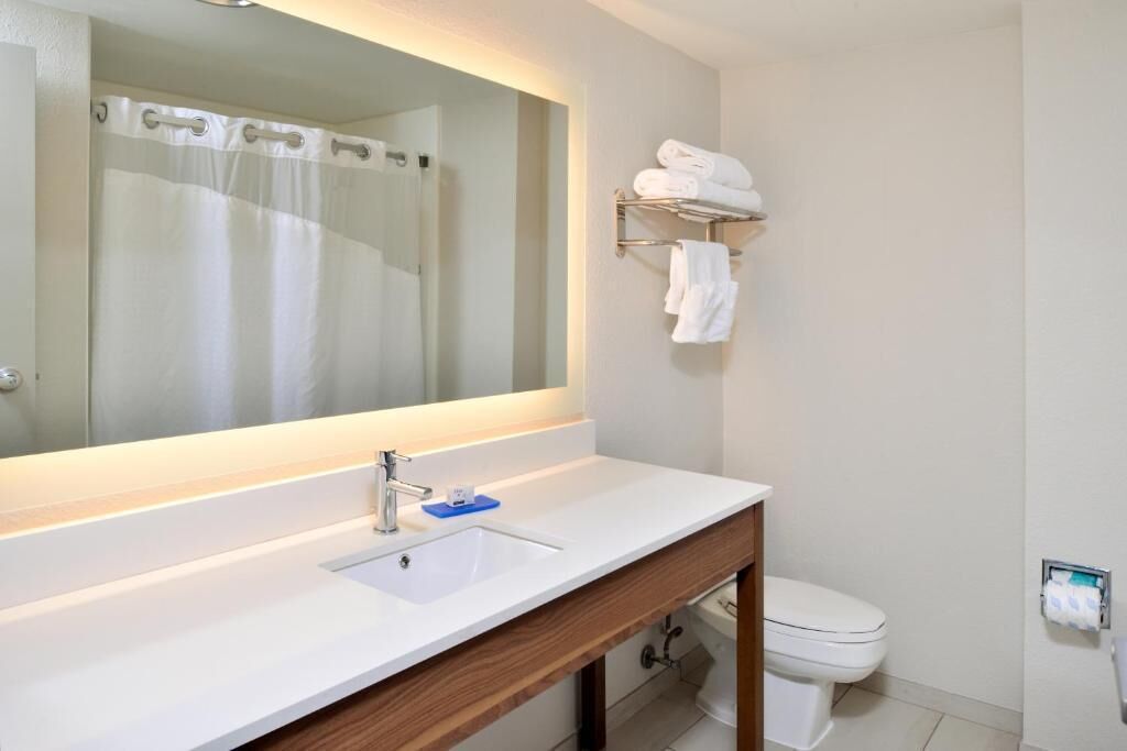 A bathroom with a white sink, mirror, and towel rack.