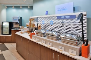 A buffet setup with labeled food stations including scrambled eggs, bacon, turkey sausage, and scrambled eggs.