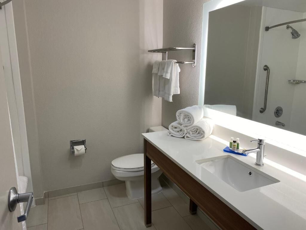 A bathroom with a white sink, a mirror, a towel rack, and a toilet.