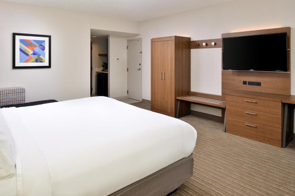 A hotel room with a large bed, a desk, a television, and a wardrobe.