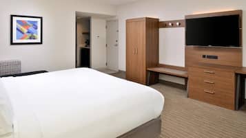 Una habitación de hotel con una cama grande, un escritorio, un televisor y un armario.
