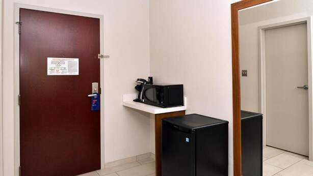 A hotel room with a door, a small white shelf with a coffee maker, a black refrigerator, and a mirror on the wall. - Holiday Inn Express Blowing Rock South by IHG (Blowing Rock)