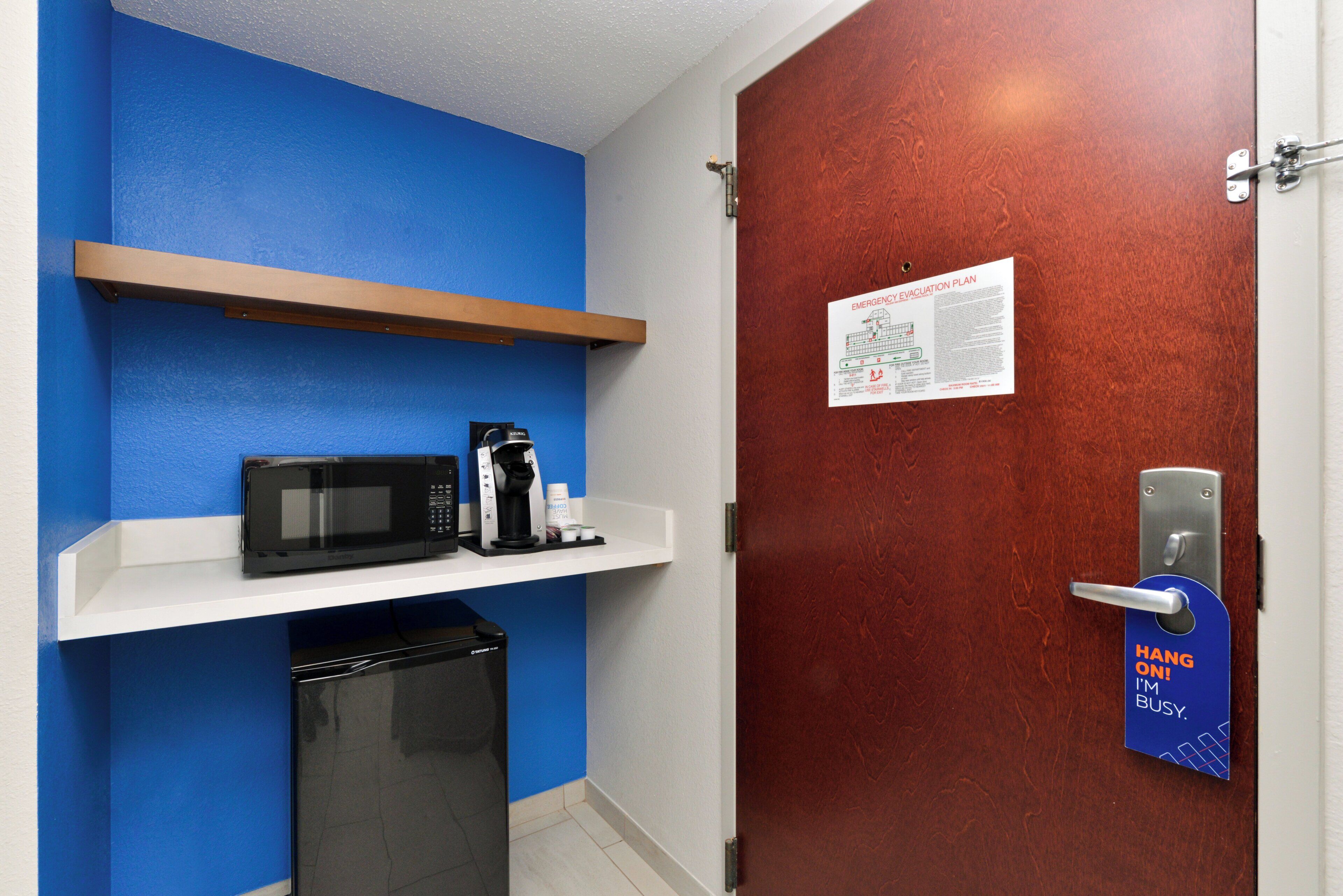 Una kitchenette equipada con microondas, cafetera y refrigerador pequeño.