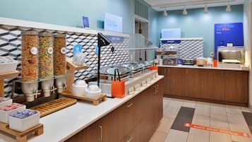 Zona de desayuno tipo buffet con diversas opciones de comida y una sección de panadería.