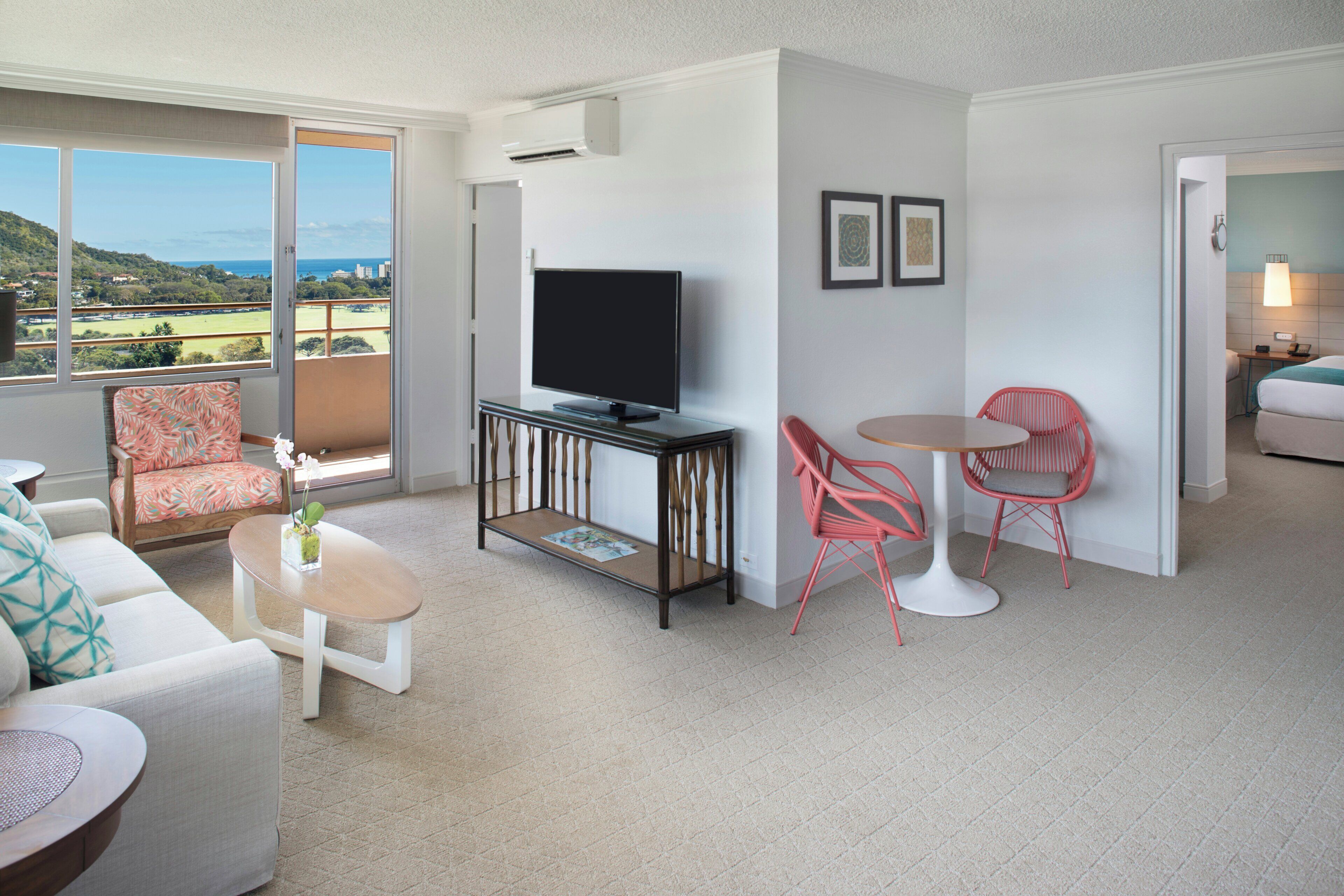 A modern living room with a television, two chairs, a sofa, and a balcony with a view.