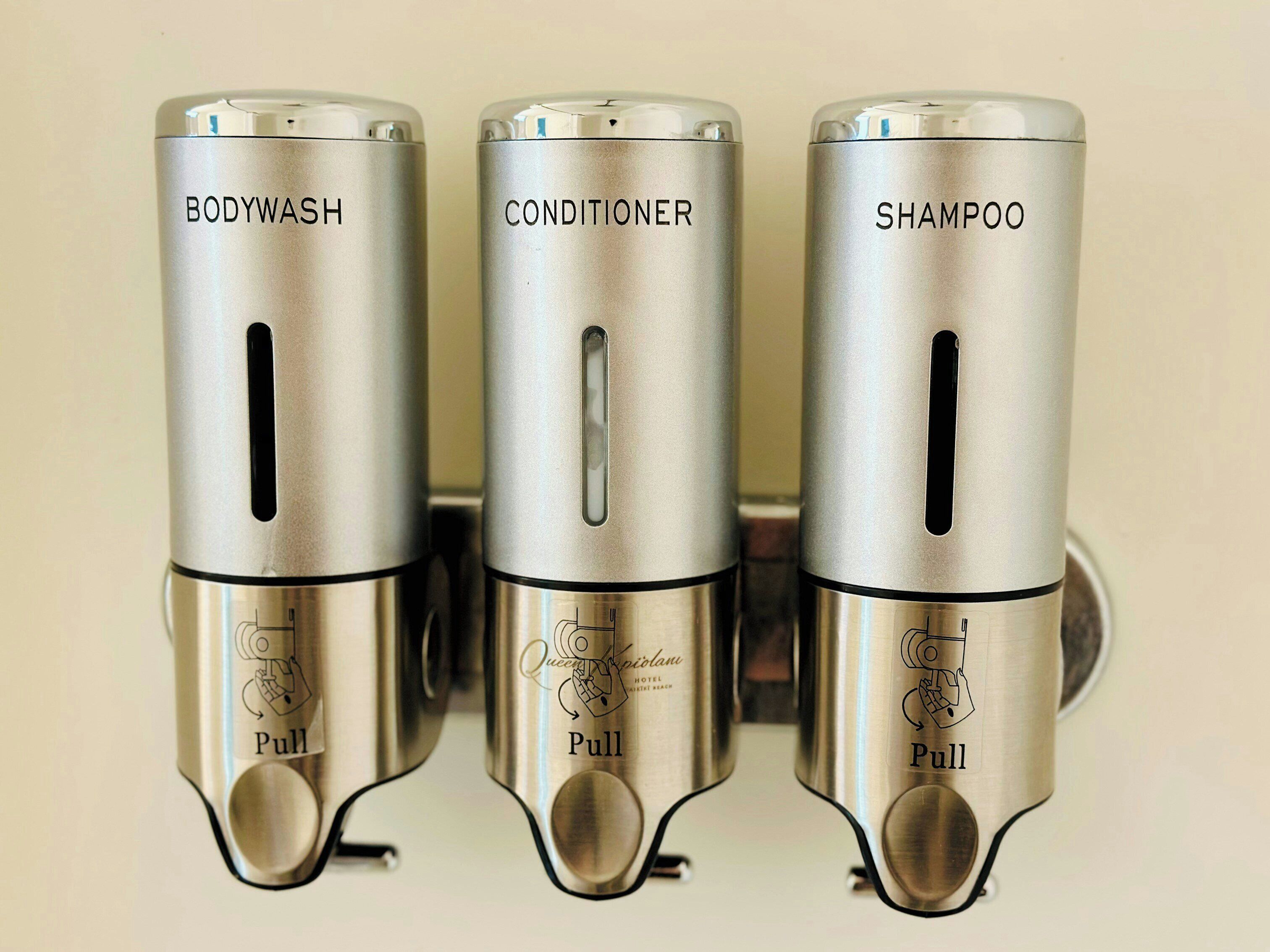 Three metallic dispensers labeled BODYWASH, CONDITIONER, and SHAMPOO.