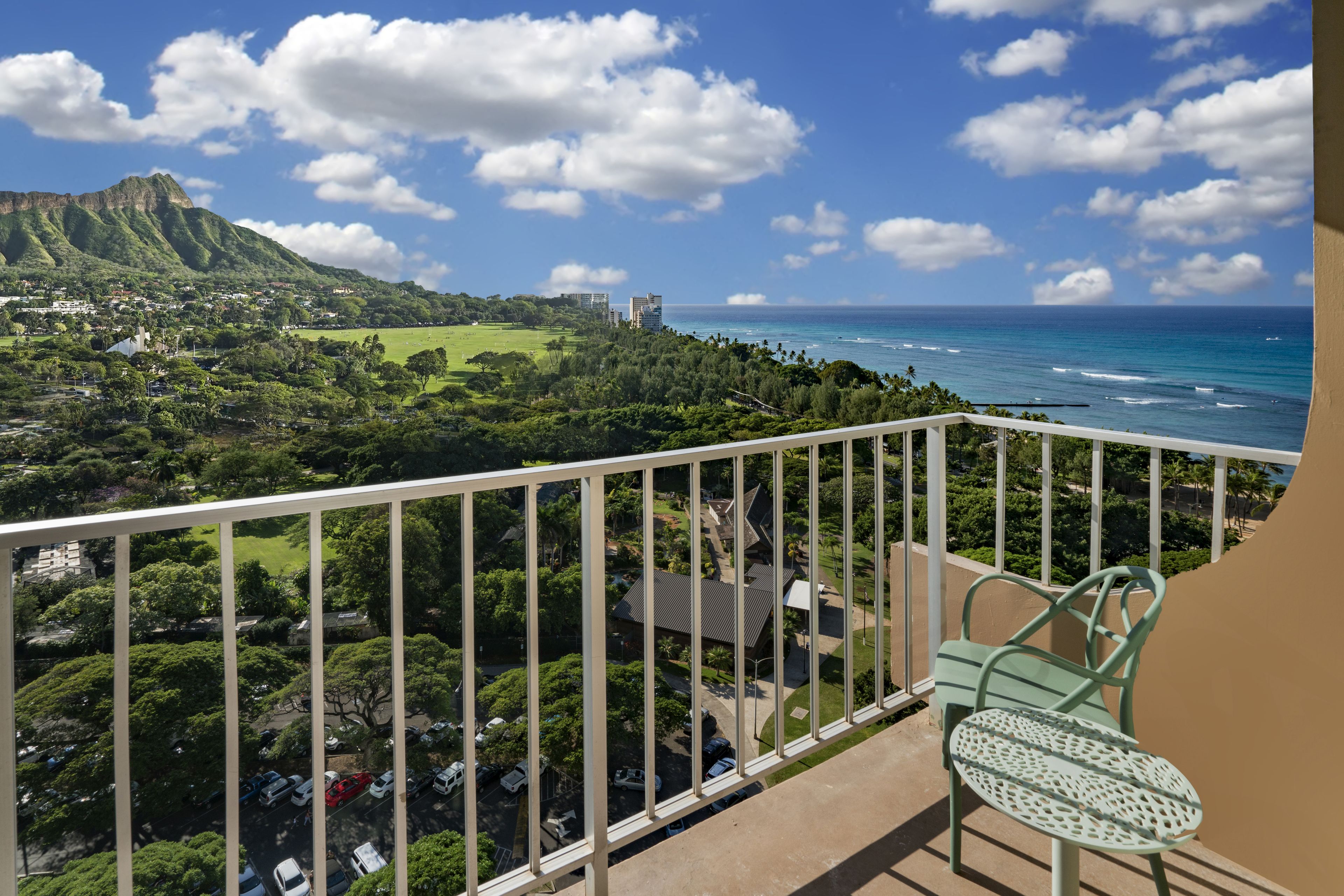 A balcony with a view of a coastal town, a mountain, and the ocean.
