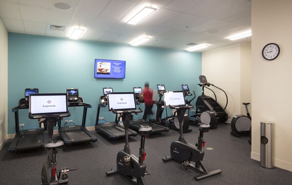 A fitness center with treadmills, stationary bikes, and an elliptical machine. - Queen Kapiolani Hotel (Honolulu)