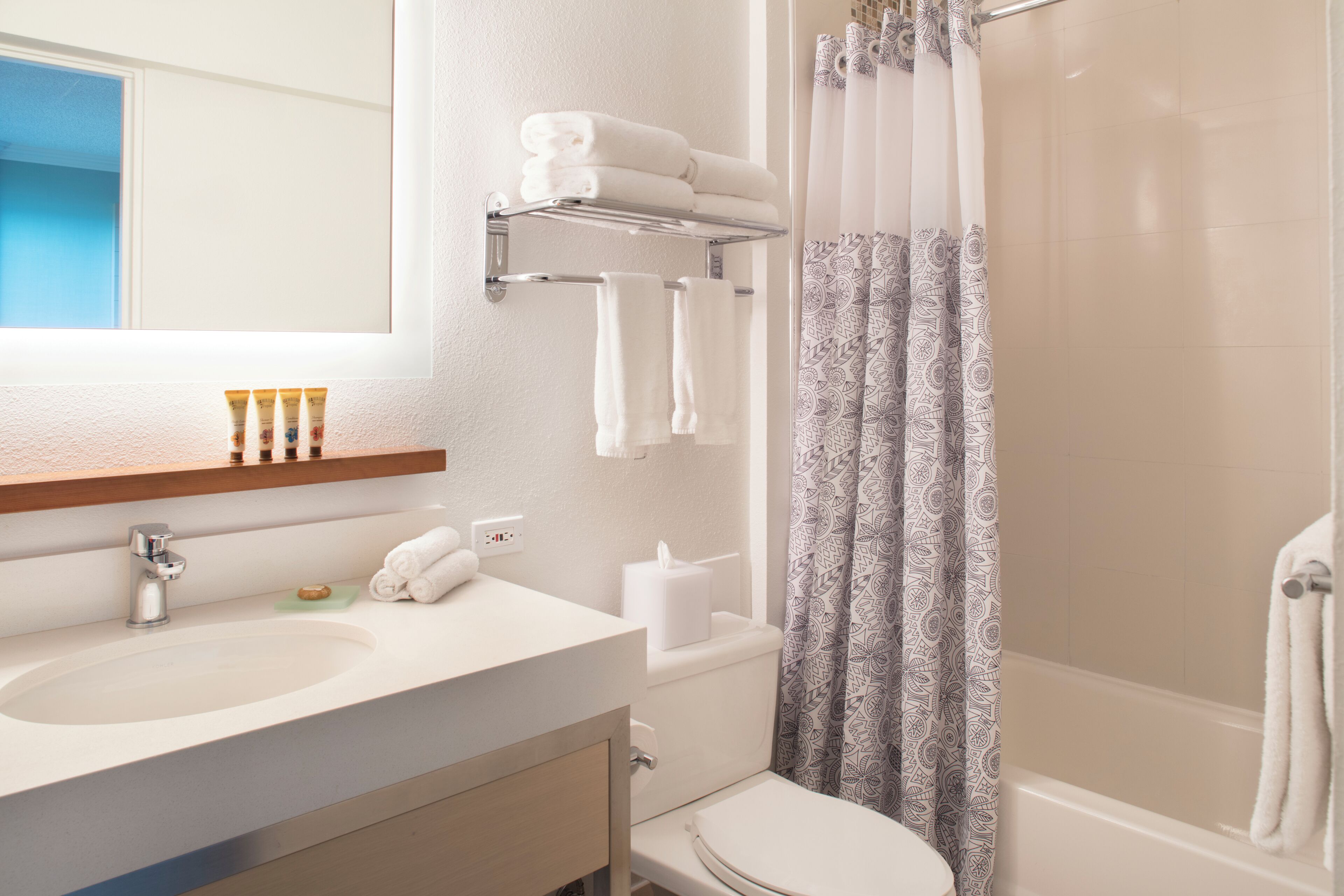 A bathroom with a sink, mirror, towel rack, toilet, and shower curtain.