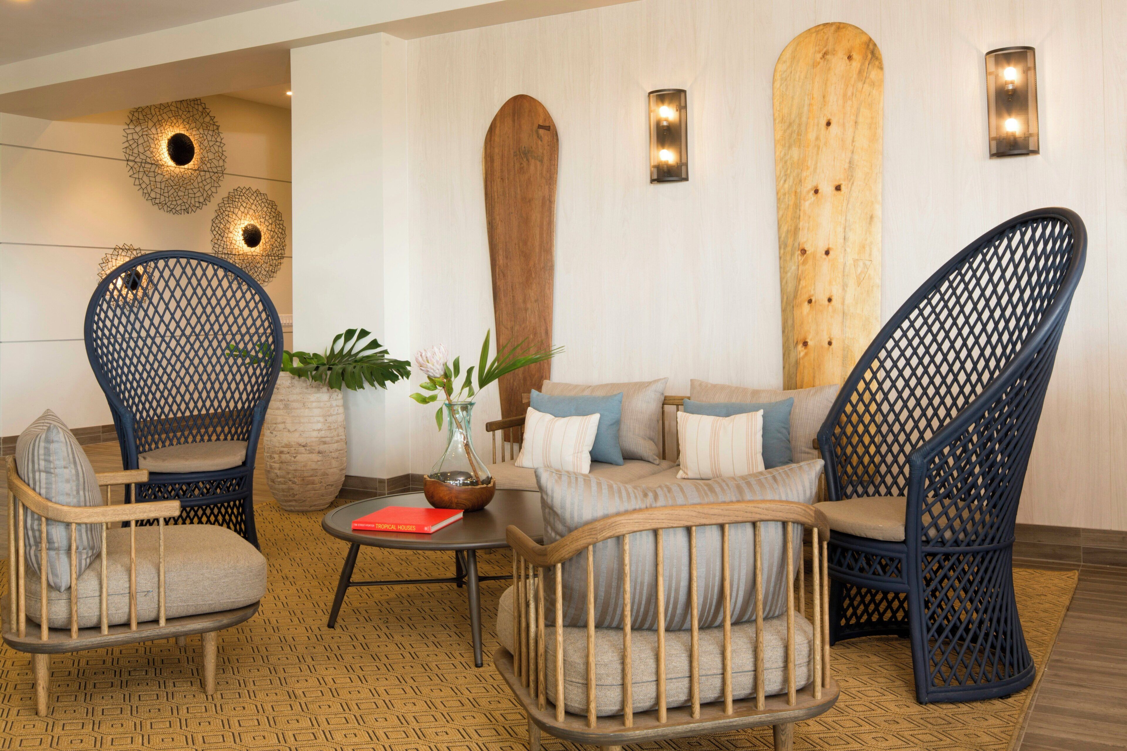 A room with a sofa, two wicker chairs, a coffee table, and decorative wall art.