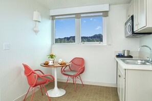 A compact kitchen with a window view, a small dining table with chairs, and a sink.