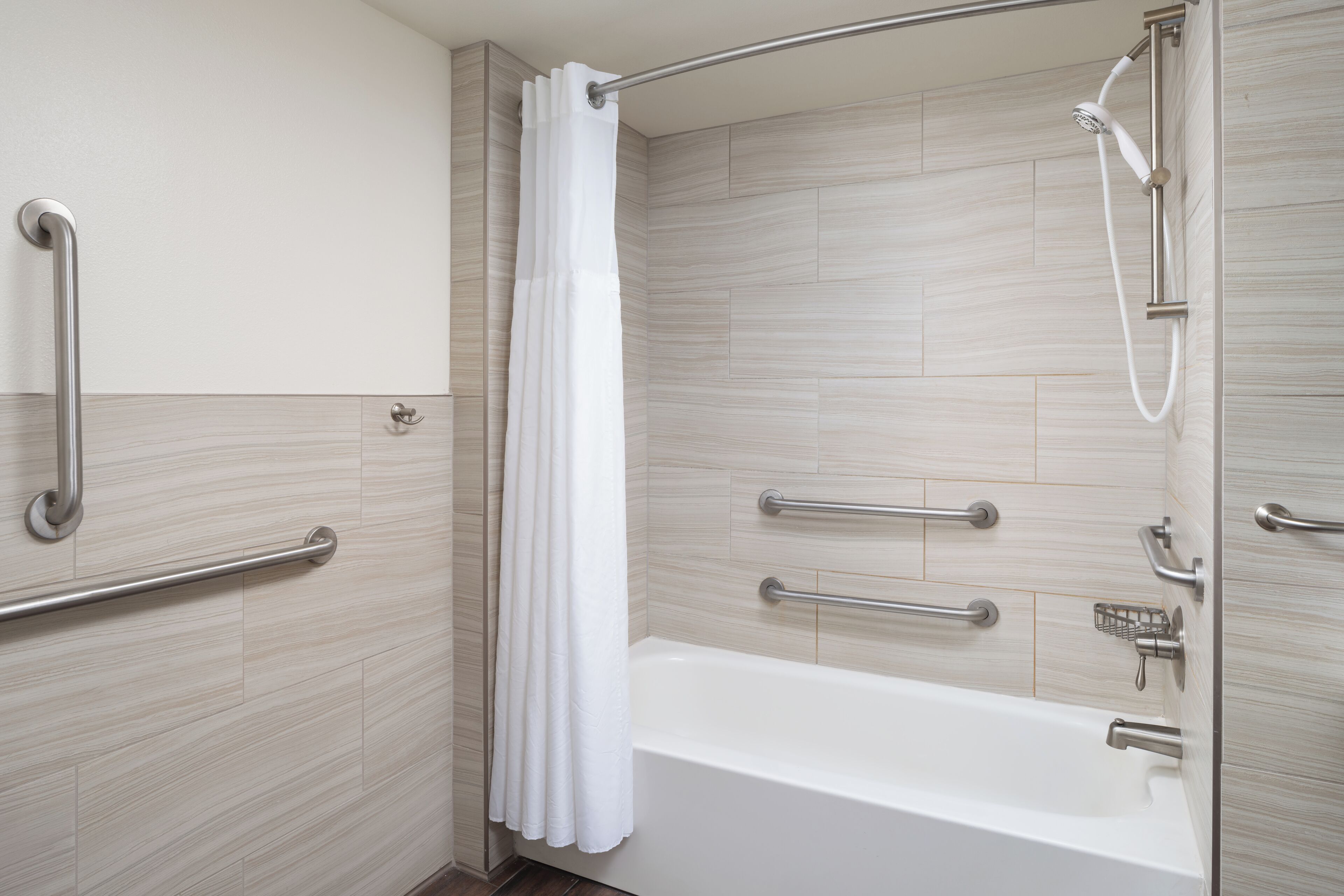 Un baño moderno con cabina de ducha, barras de apoyo y bañera.