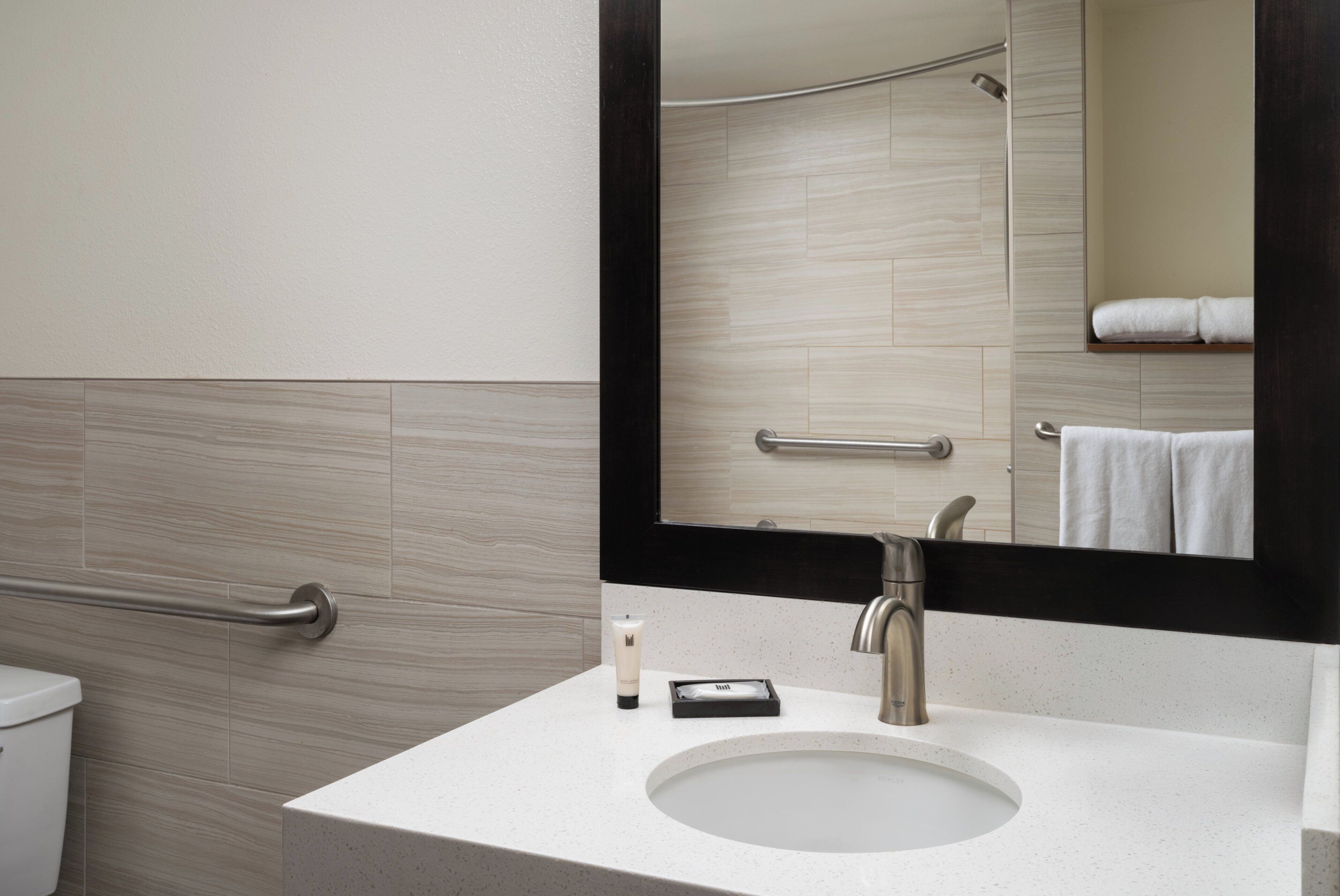 A bathroom with a white sink, a mirror, and a towel rack.