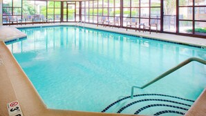 An indoor swimming pool with clear blue water, a pool ladder, and lounge chairs along the poolside. - Courtyard By Marriott Ann Arbor (Ann Arbor)