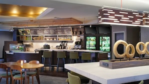 A modern bar area with a long counter, stools, and a display of circular wooden objects. - Courtyard By Marriott Ann Arbor (Ann Arbor)