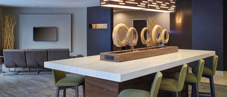 A modern kitchen with a large island, bar stools, a flat-screen TV, and decorative wooden rings.