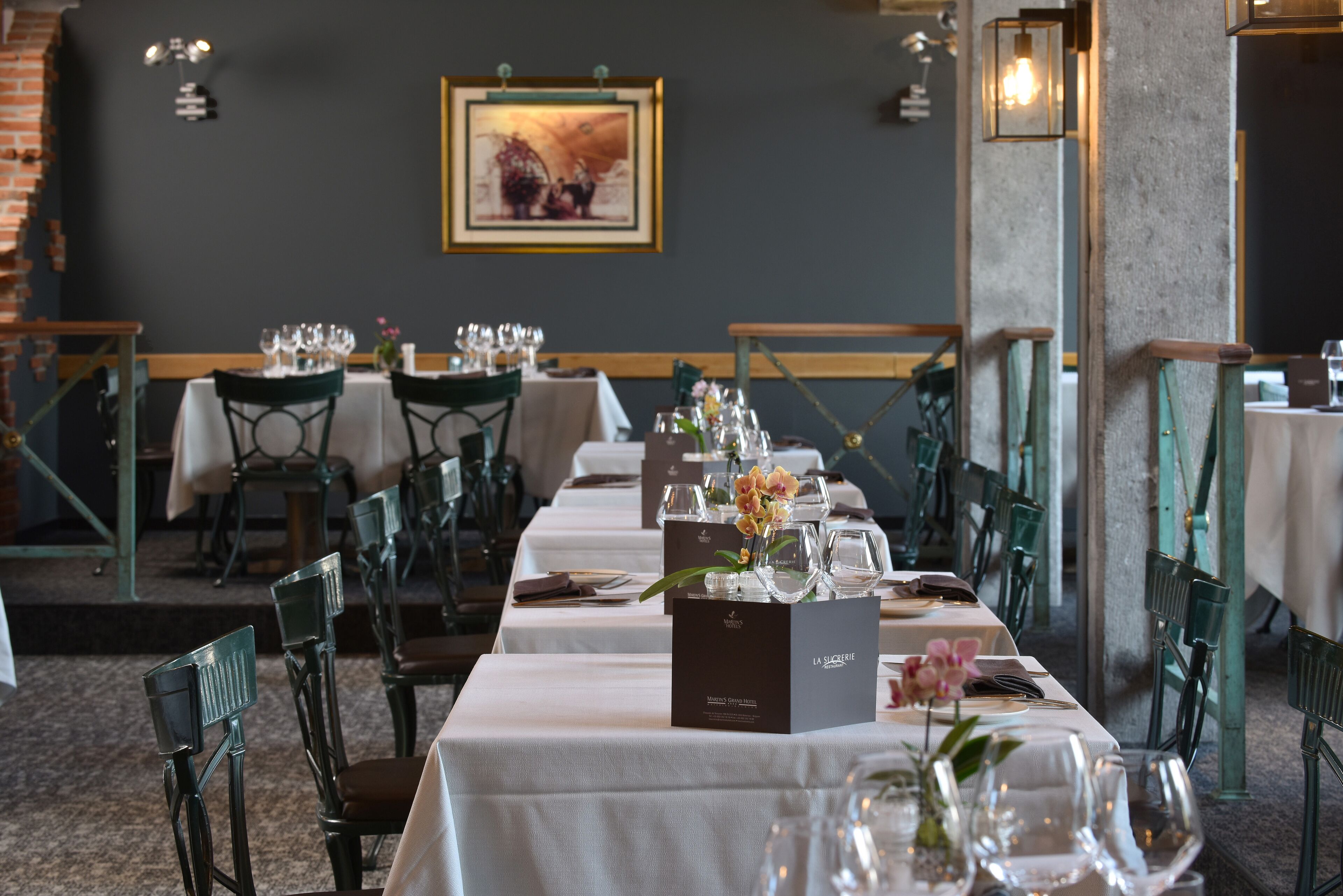 A restaurant with tables set for dining, chairs, and a framed picture on the wall.