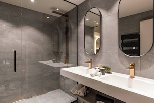 Une salle de bain moderne avec un grand miroir, deux lavabos et une douche.