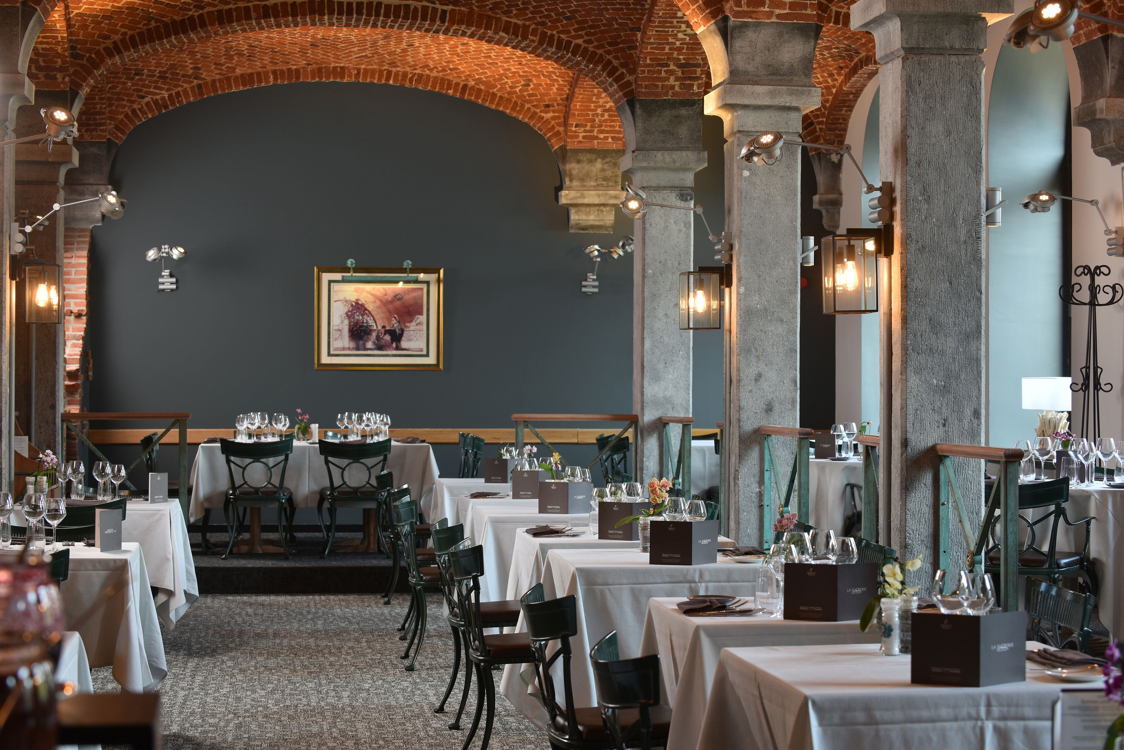 A restaurant with tables set for dining, featuring a brick ceiling and a framed artwork on the wall.