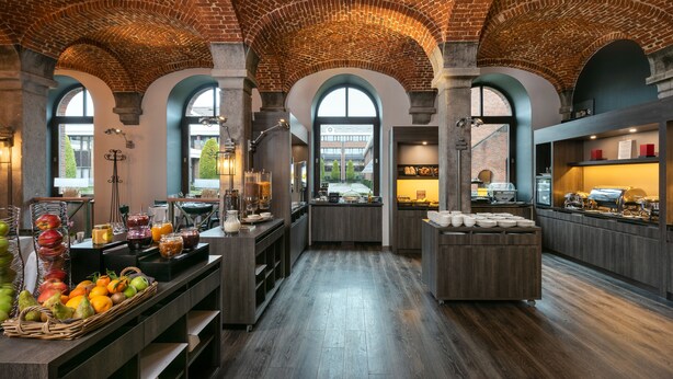 A spacious kitchen with a brick ceiling, large windows, and wooden flooring. - Van der Valk Waterloo (Waterloo)