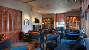 A hotel lobby with blue seating, wooden cabinets with glass doors, and a fireplace. - Van der Valk Waterloo (Waterloo)