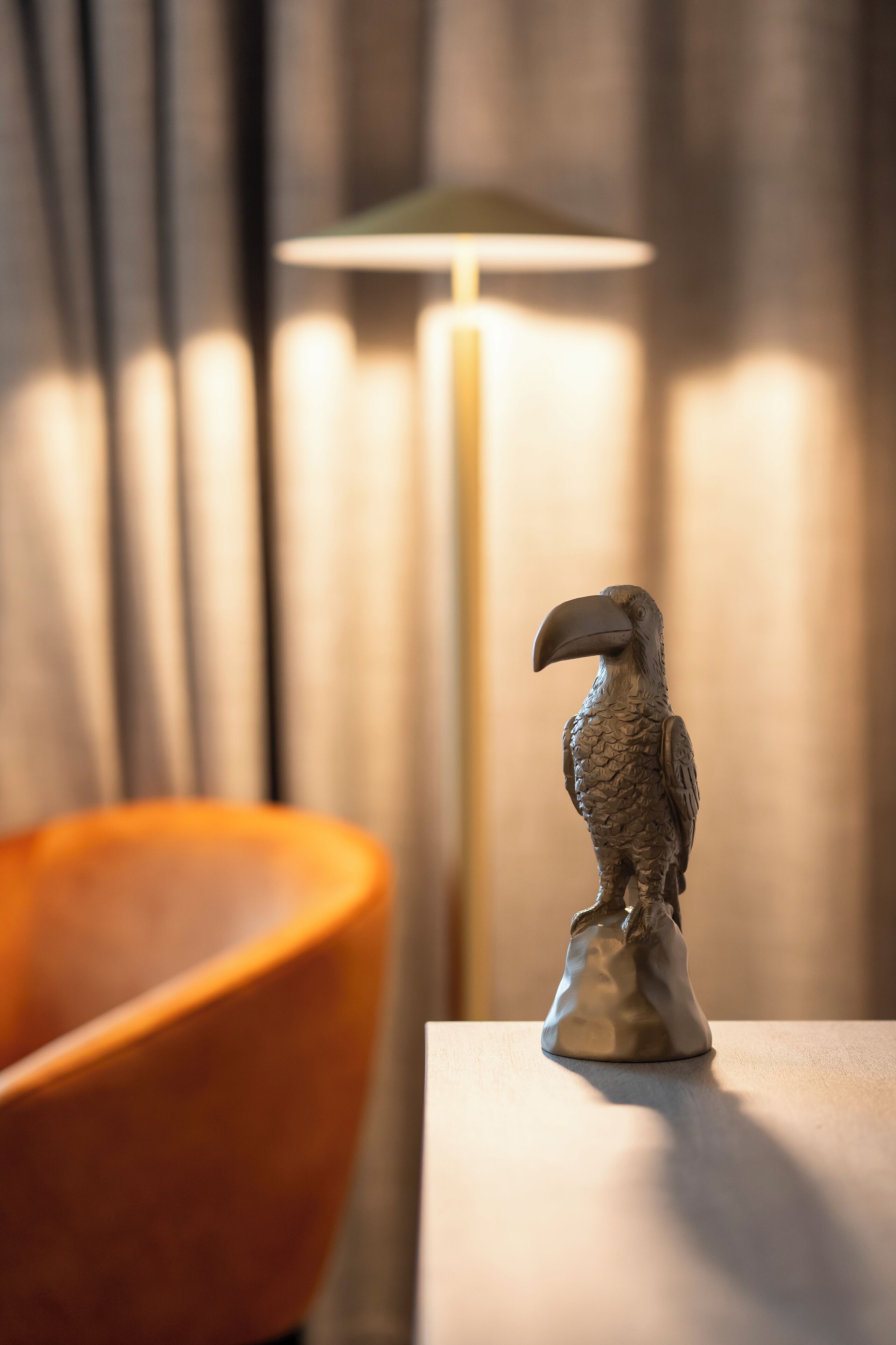 Una scultura a forma di uccello su un tavolo, con una lampada sullo sfondo.